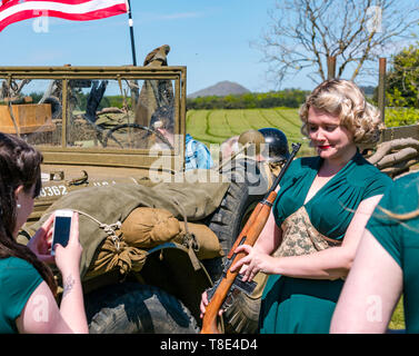 East Lothian, Großbritannien. Mai 2019. Kriegserfahrung: Ein Ereignis mit allen Dingen, die mit den Weltkriegen zusammenhängen. Amerikanische Fahrzeuge der US-Armee aus dem zweiten Weltkrieg sind zu sehen. Sänger die Ragtime Dolls Gesangsgruppe fotografiert mit einem Gewehr Stockfoto