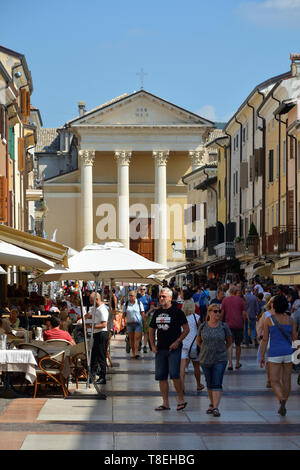 Touristen auf der Piazza Giacomo Matteotti mit der Kirche San Nicolo und Severo Bardolino am Gardasee - Italien. Stockfoto