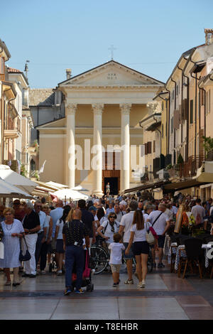 Touristen auf der Piazza Giacomo Matteotti mit der Kirche San Nicolo und Severo Bardolino am Gardasee - Italien. Stockfoto