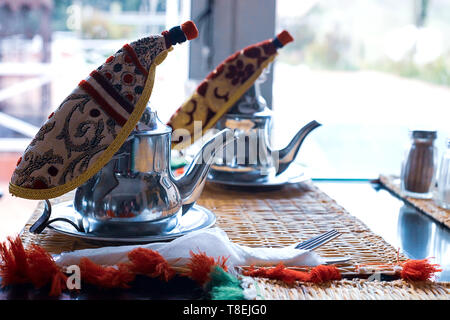 Marokkanischen Tee mit Minze und Zucker in einer Brille auf eine Kupferplatte mit Wasserkocher. Marokko Stockfoto