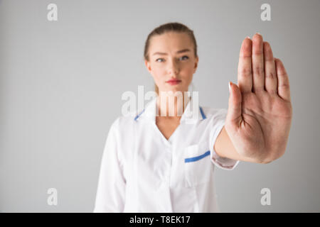 Foto von einer schönen jungen Frau cosmetologist Arzt über graue Wand Hintergrund angezeigt stop Geste isoliert. Stockfoto