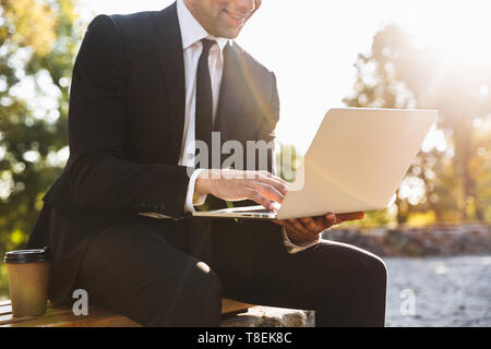 Zugeschnittenes Bild von ein hübscher junger Geschäftsmann Walking im Freien mit Laptop Computer. Stockfoto