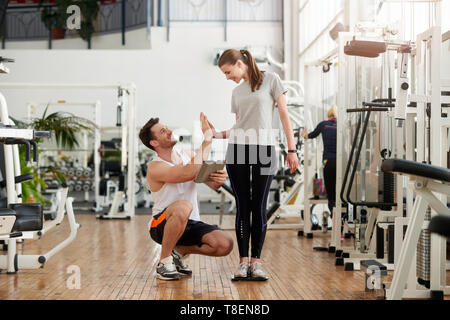 Glückliche Frau feiern Gewichtsverlust. Frau mit Personal Trainer geben hoch fünf. Personal Fitness leistung Konzept. Stockfoto