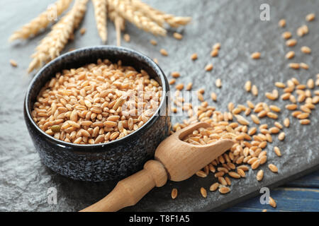 Schüssel und Schaufel mit Weizenkörner auf Tisch Stockfoto