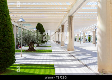 Der Innenhof am Flughafen, ein Platz zum Rauchen und zum Boarding draußen warten. Moderne Architektur mit Metall Säulen und Balken. Mit Nadelbäumen, kleinen Rasenflächen und Pavillon eingerichtet. Stockfoto