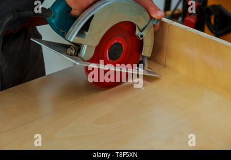 Installation der Küche. Arbeitnehmer mit kreisförmigen Elektro Säge kitchen cabinet Stockfoto