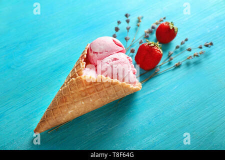 Waffel Kegel mit leckeren Erdbeer Eis und Lavendel auf Farbe Holz- Hintergrund Stockfoto