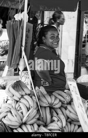 Port of Spain, Trinidad und Tobago - November 28, 2015: lächelnde Frau afrikanische amerikanische verkauft gelbe Banane Obst auf lokalen Süden Markt im Freien Stockfoto