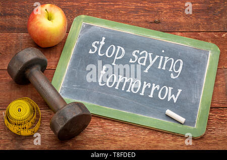 Aufhören, morgen - weißer Kreide Text auf einer Schiefertafel Schultafel gegen verwitterte Rot lackiert Scheune Holz mit einer Hantel, Apple und Maßband Stockfoto