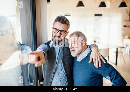 Ein Porträt von Erwachsenen hipster Sohn und Vater in Innenräumen zu Hause, sprechen. Stockfoto