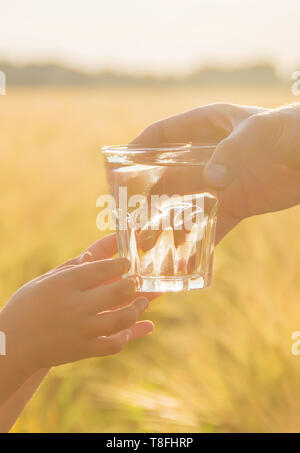 Der Vater gibt das Kind ein Glas Wasser. Selektive konzentrieren. Natur. Stockfoto