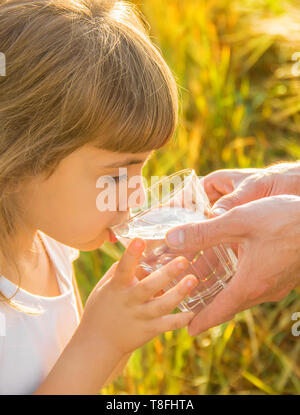 Der Vater gibt das Kind ein Glas Wasser. Selektive konzentrieren. Natur. Stockfoto