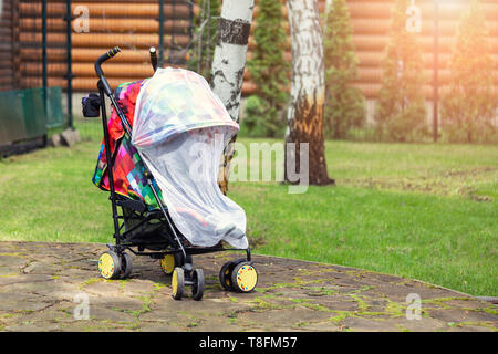 Kind im Kinderwagen mit schützenden Netz während Spaziergang abgedeckt. Kinderwagen mit Anti-mücken-Abdeckung. Midge-Schutz für Kinder während Outdoor Stockfoto