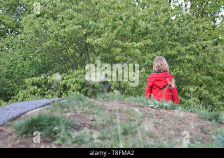 Wenig kleinkind Mädchen in einem Rad-mantel Wandern in der Natur ganz allein, von ihrer eigenen, von hinten gesehen Stockfoto