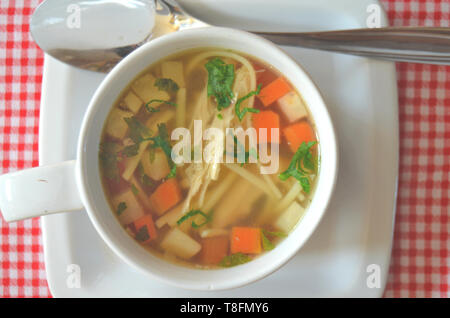 Traditionelle tschechische Hühnersuppe mit Hühnerbrühe, hausgemachte Nudeln, Karotten, Sellerie, persil Wurzel, Hähnchenfleisch und gehackter frischer Persil - in einem whi Stockfoto