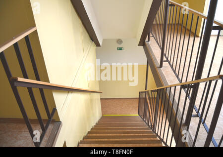 Treppe in einem Korridor eines durchschnittlichen Tschechischen alten kommunistischen konkrete Panel Building Blocks (panelak), mit braunem Geländer, gelbe Wände und Notausgang Stockfoto