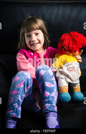 Nettes Mädchen mit ihr Spielzeug auf dem Sofa zu Hause Stockfoto