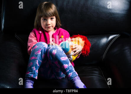 Nettes Mädchen mit ihr Spielzeug auf dem Sofa zu Hause Stockfoto