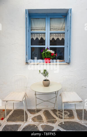 Weiße Haus Fassade mit blauen Fenster, Tisch und Stühlen in Naoussa, Paros, Kykladen Stockfoto