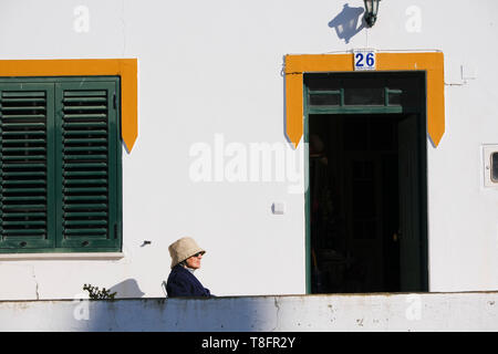 Frau sitzt im Winter Sonnenschein, Mértola, im Südosten der Region Alentejo, Portugal. Mértola liegt in der Parque Natural do Vale do Guadiana. Stockfoto