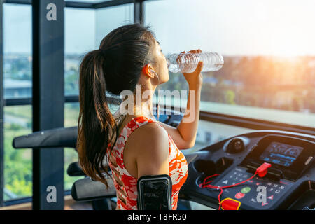 Junge Frau trinkt Wasser in der Turnhalle. Übung Konzept. Stockfoto