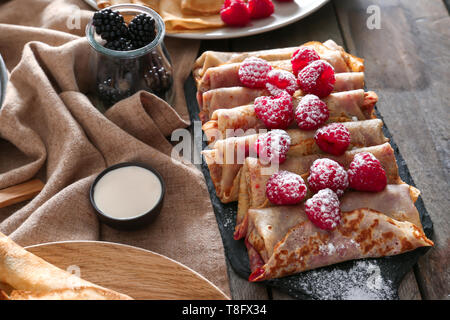 Mit leckeren dünne Pfannkuchen und Beeren auf hölzernen Tischplatte Stockfoto