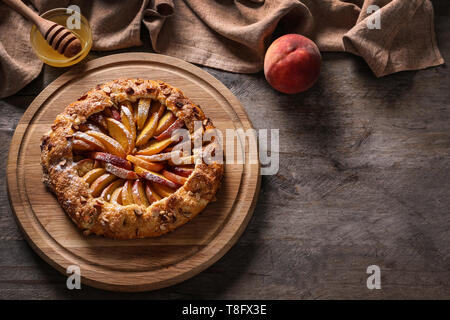 Vorstand mit köstlichen Pfirsich Galette und Honig auf hölzernen Tisch Stockfoto