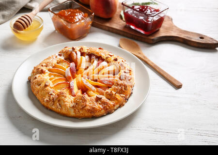 Mit köstlichen Pfirsich Galette, Honig und Marmelade auf hölzernen Tischplatte Stockfoto