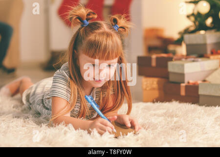 Süße kleine Mädchen schreiben Brief an Santa Claus zu Hause Stockfoto