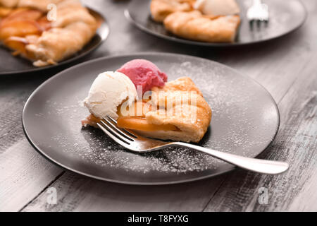 Platte mit Stück der köstlichen Pfirsich Galette und Eis auf hölzernen Tisch Stockfoto