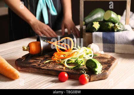 Frische Zucchini und Karotten Spaghetti mit Spirale Reibe auf hölzernen Tisch Stockfoto