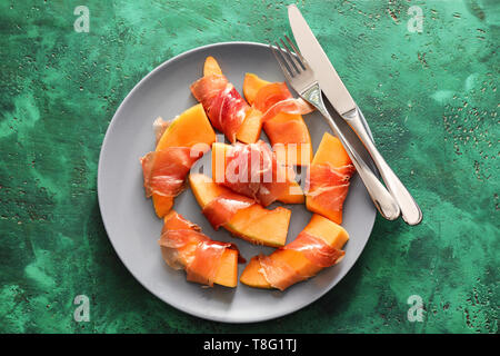 Leckere Melone eingewickelt in Schinken auf Platte Stockfoto