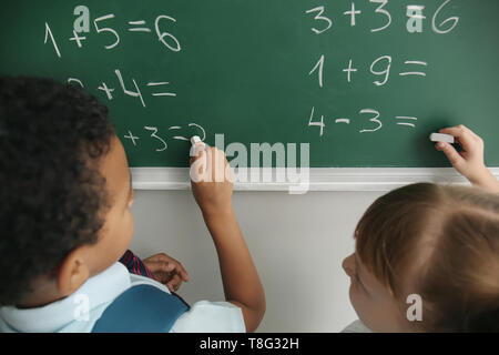 Die Schüler schreiben auf der Schiefertafel im Klassenzimmer während Mathe Lektion Stockfoto