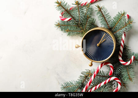 Zusammensetzung mit Wecker, Tannenzweigen und Zuckerstangen auf hellen Hintergrund. Christmas Countdown Stockfoto