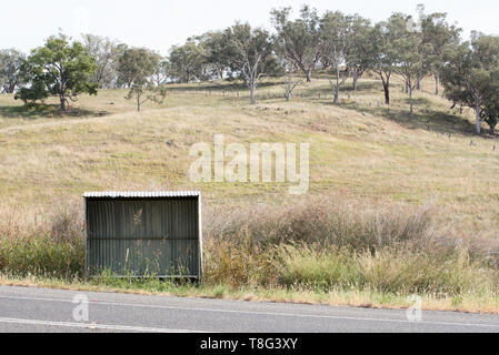 Eine einsame Leere Wellblech Bushaltestelle durch langes Gras umgeben, in der Nähe einer Koppel in regionalen New South Wales, Australien Stockfoto