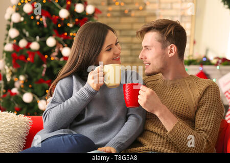 Nettes junges Paar trinken heiße Schokolade zu Hause am Heiligabend Stockfoto