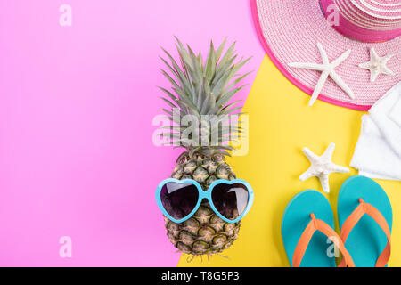 Strand Zubehör Ananas, Sonnenbrille, Flip Flop, starfish Beach Hut und Sea Shell auf Rosa und gelbem Hintergrund für Sommerurlaub und Urlaub con Stockfoto