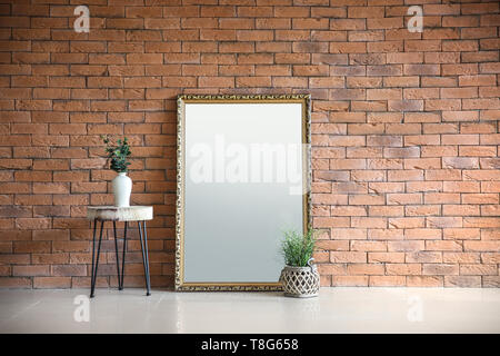 Großen eleganten Spiegels mit grünen Pflanzen in der Nähe der Wand im Zimmer Stockfoto