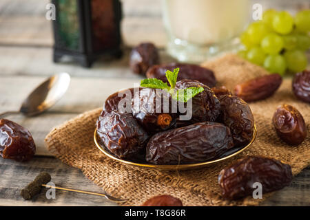 Ramadan Essen und Getränke Konzept. Ramadan Termine Laterne mit Milch, Obst, Trauben und Minze auf hölzernen Tisch Hintergrund. Stockfoto