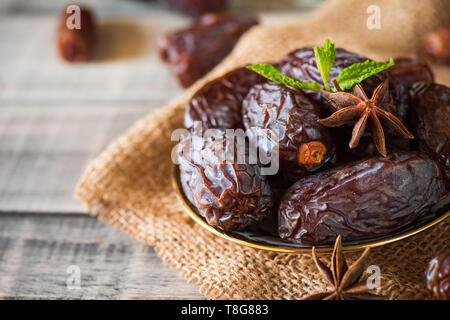 Ramadan Essen und Getränke Konzept. Termine Obst und grüne Minze in einer Schüssel auf hölzernen Tisch Hintergrund. Stockfoto