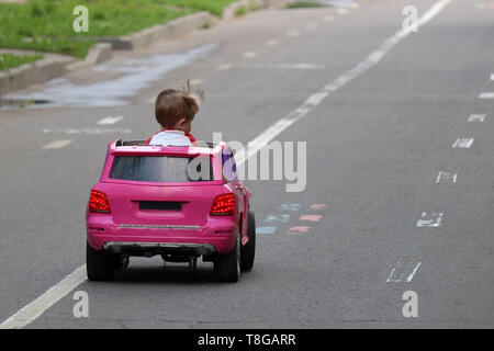 Little Boy driving big Spielzeug Auto auf einer Straße. Kid spielen im Freien im Sommer, Konzept des Lernens fahren, Fahranfänger Stockfoto