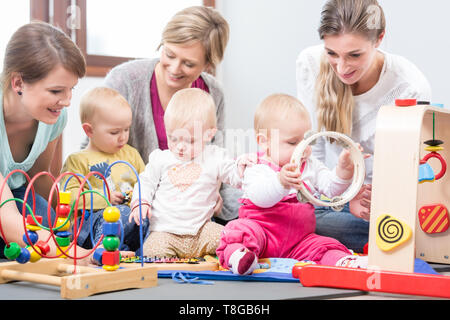 Drei glückliche Mütter ihre Babys spielen mit sicheren bunte Spielzeug beobachten Stockfoto