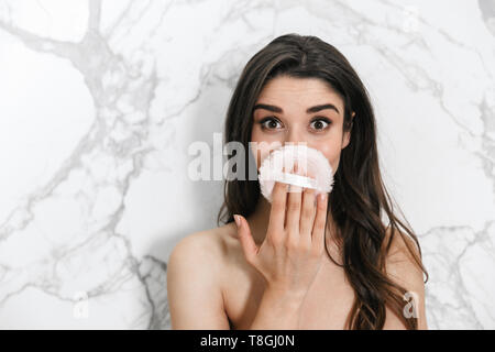 Schöne junge Frau in ein Handtuch über Marmor Hintergrund gewickelt, mit Powder Puff Stockfoto