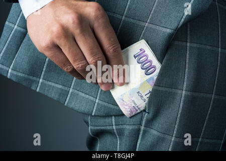Nahaufnahme eines jungen Geschäftsmann, tragen einen eleganten grauen Anzug, oder einige Tschechische Kronen Banknoten in die Tasche seiner Hose Stockfoto