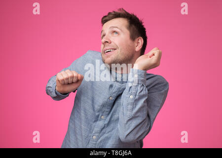 Junge Mann tut, auf rosa Wand zu tanzen Stockfoto