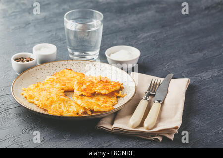 Hommade Kartoffelpuffer - Rösti, Bratkartoffeln, Kartoffelpuffer, latkes, draniki - mit Sauerrahm auf grauem Hintergrund Stockfoto