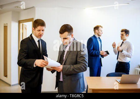 Geschäftsmann mit seinem Kollegen steht mit Dokumenten und es diskutieren. Stockfoto