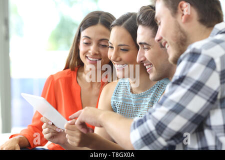 Happy Gruppe von Freunden überprüfen Tablette Inhalt auf einer Couch zu Hause sitzen Stockfoto