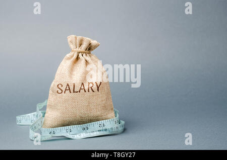 Geld beutel mit dem Wort Gehalt und Maßband. Lohnkürzungen. Das Konzept der begrenzten profitieren. Mangel an Geld und Armut. Kleine Einkommen. Gehaltskürzung. Stockfoto