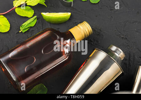 Rum, Cuba Libre, Flasche dunkler Rum, Set, für Cocktail, Stein Hintergrund, schwarzer Hintergrund, Rum, Flasche, dunkler Rum, Kalk, Eis, Minze, Shaker Kalk, Eis Stockfoto
